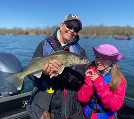 an angler and a kid on a boat, with a walleye