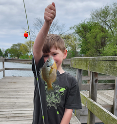 kid with a sunfish he caught on a dock