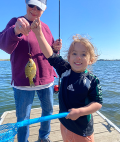 young angler excited to have caught a fish, with her great grandma behind her