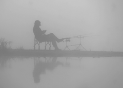 a foggy scene with a person fishing with a pole holder and what appears to be two fishing poles