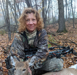 hunter with a deer she harvested with a crossbow