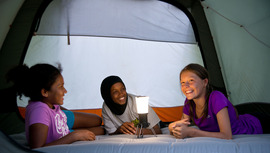 Three young people hanging out in a tent.