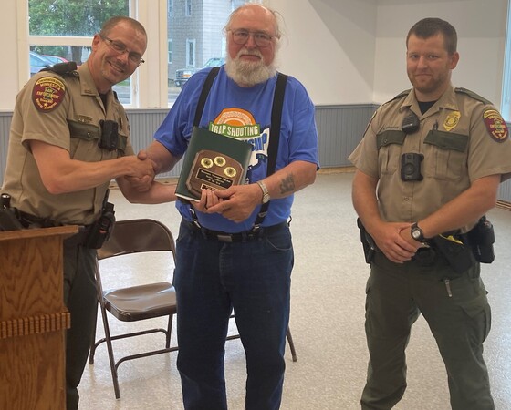 Two conservation officers hand an award to a man