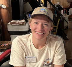 A woman smiling and sitting at a desk full of papers