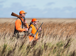 an adult and kid pheasant hunting in tall grass