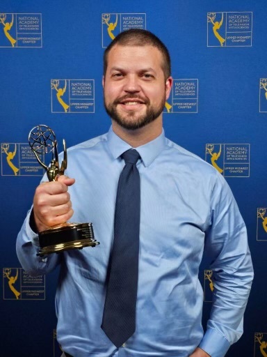 A man in a blue shirt holding a golden statue