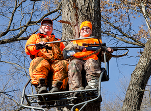 a pair of hunters in a tree stand in blaze orange