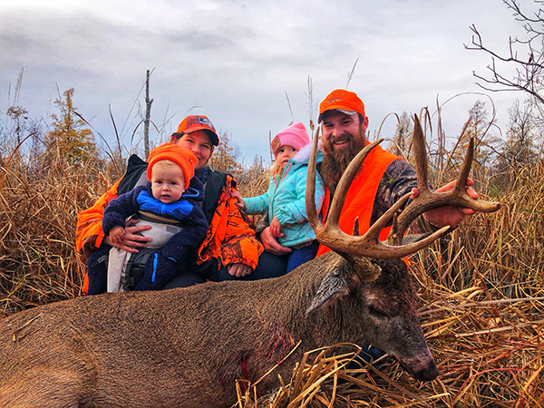 parents and two kids with a large deer the dad harvested