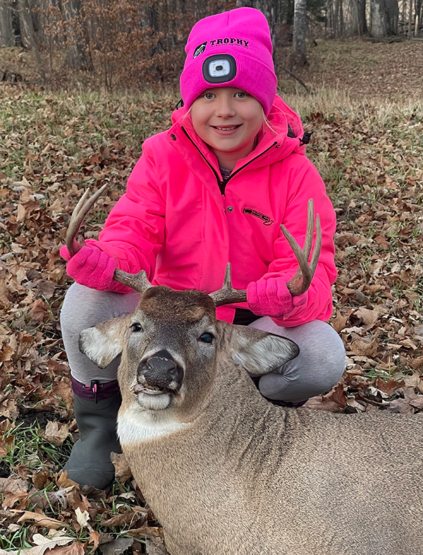 young hunter in blaze pink with a deer she harvested