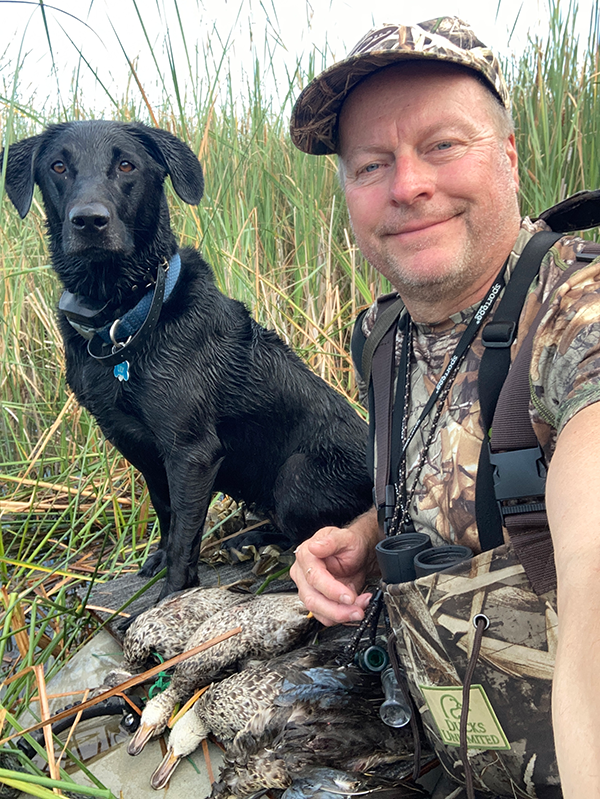 duck hunter with a bird dog in the marsh