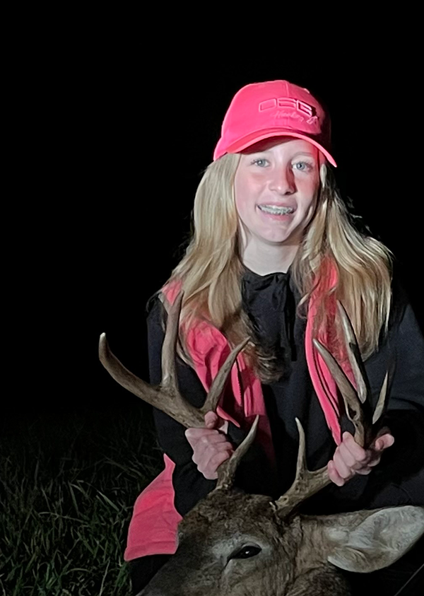 hunter in blaze pink with the deer she harvested 