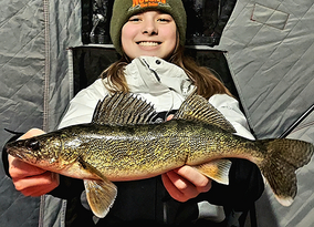 angler with a walleye she caught in a portable ice shelter