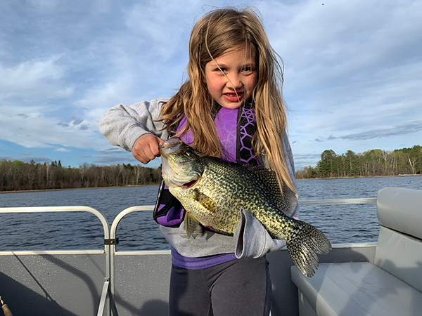 girl holding a huge crappie on a pontoon boat