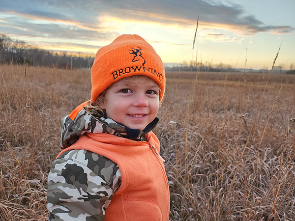 kid wearing blaze orange in a field