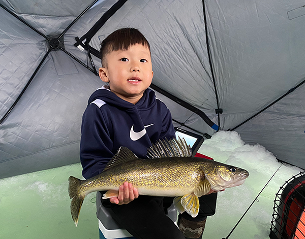 young angler with a large walleye caught ice fishing