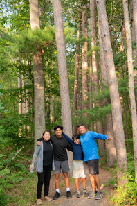Latino family posing in pine grove in the summer at St. Croix State Park.