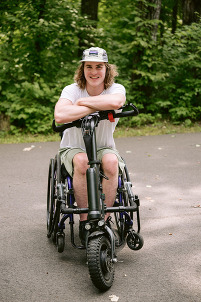 Young man on wheelchair on a trail, in the woods.