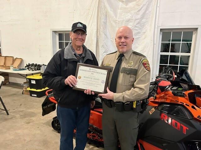 A man and a conservation officer holding a plaque