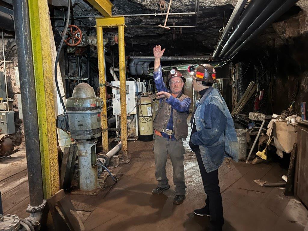 Two men in a cave with mechnical equipment all around