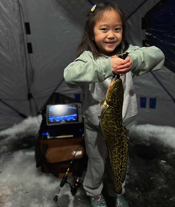 young kid holding a burbot caught while ice fishing