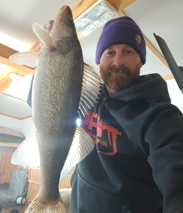 angler holding a walleye caught ice fishing