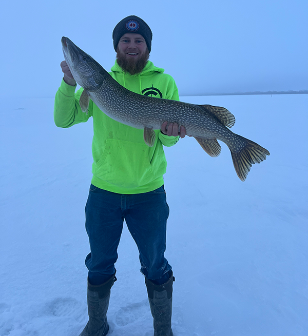 angler holding a pike on the ice