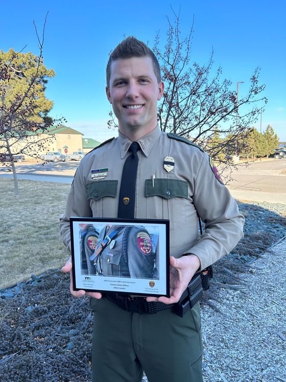 A man in a conservation officer uniform holding an award plaque