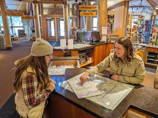 A Parks and Trails Associate helps a visitor in the ranger station at Itasca State Park