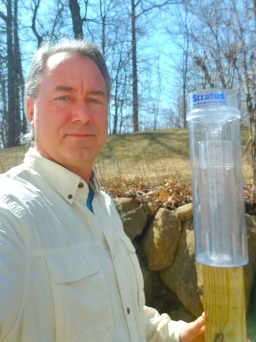 A man holds up a rain gauge
