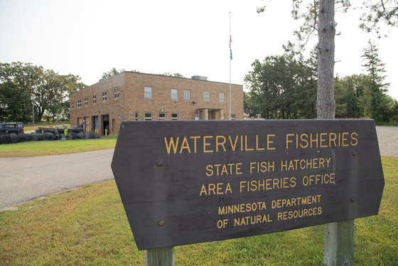 A sign which says Waterville State Fish Hatchery in front of a building
