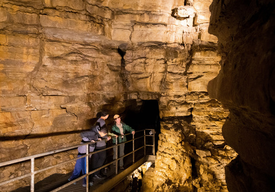 A park naturalist leads an underground tour for two teens through Mystery Cave. 