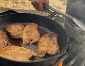 fish frying on a cast-iron skillet