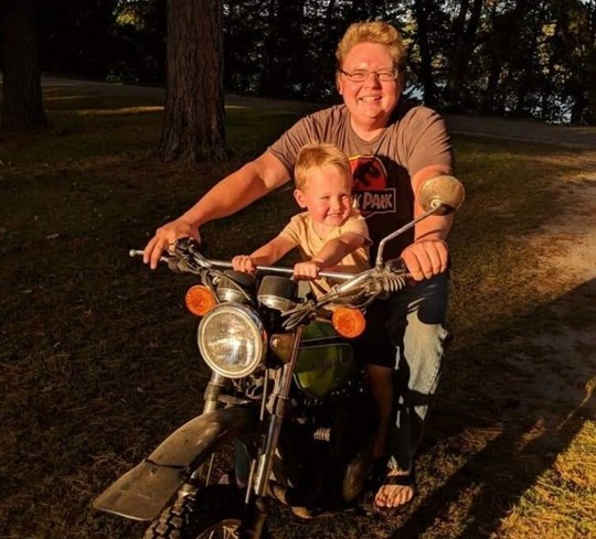 A man and a toddler smiling on a bike