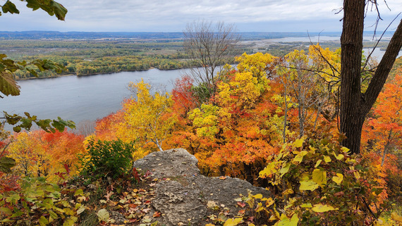 Looking out at a river from a high vantage point with bright fall colors all around. 