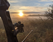 archery hunter photo of bow and arrow looking at foggy grass at sunrise