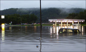 Floodwaters above cars and near top of gas station 