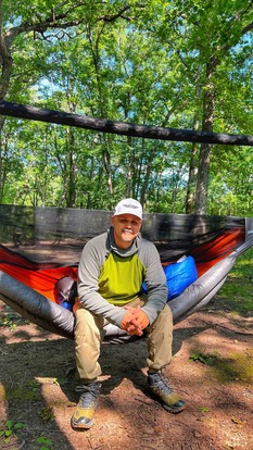 Rob sits on his hammock and smiles at the camera. 