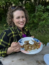 Amber smiles while holding up a plate of apple crisp. 