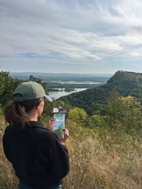 Beth paints a small canvas while looking out at a bluff along the river. 