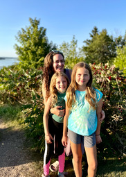 Heidi and her two children stand outside smiling. 