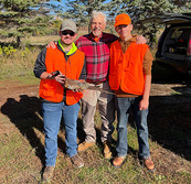 hunter mentor with two younger hunters and one holding a harvested pheasant