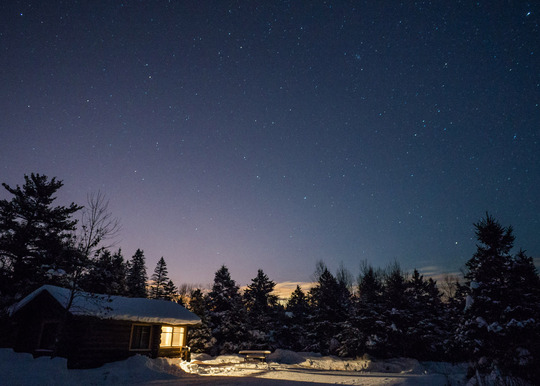 A snow-covered camper cabin at twilight. 