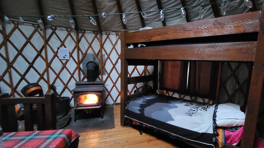 The inside of a yurt shows a fireplace burning brightly.