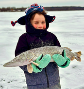 young angler with a big pike he caught on the ice