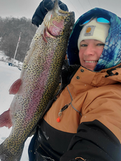 angler with a large rainbow trout she caught on the ice