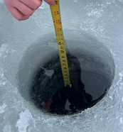 hole in the ice with a tape measure in the hole