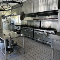 An empty but clean, all stainless steel commercial kitchen.