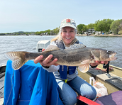 smiling angler holding a sauger she caught on a boat