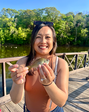 smiling angler holding a sunfish she caught on a dock