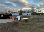 a CWD station with a head barrel, dumpster, quartering station and table, map and CWD Sampling Station sign